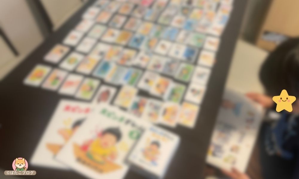 大ピンチずかん（絵本）とカルタを並べて、内容を見比べながら遊んでいる様子（ぼかし加工）